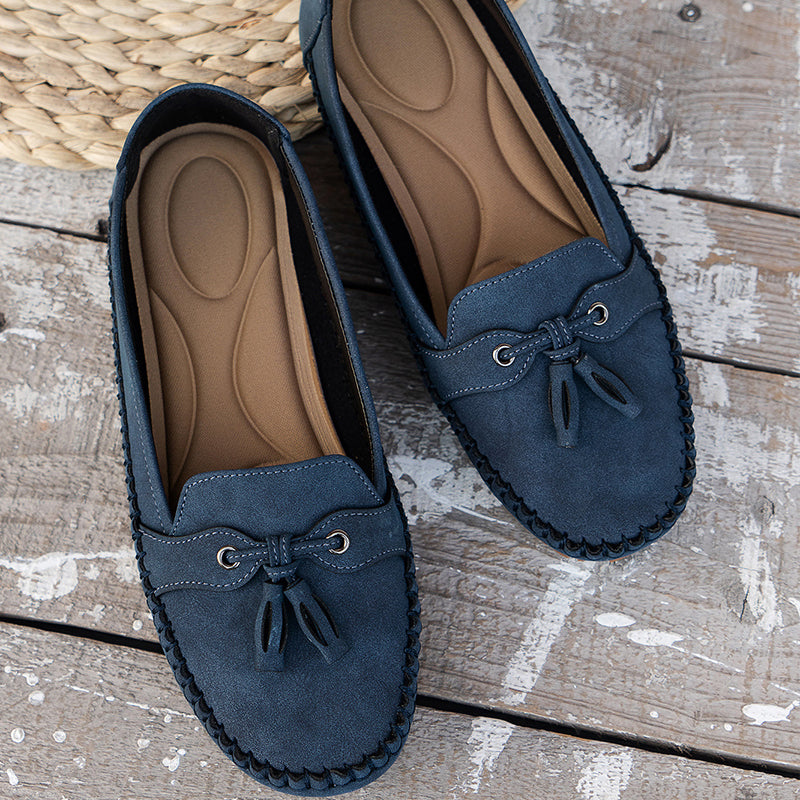 Mocassins en cuir bleu marine pour femmes sur plancher en bois, avec semelle intérieure confortable et nœud décoratif, style décontracté élégant.