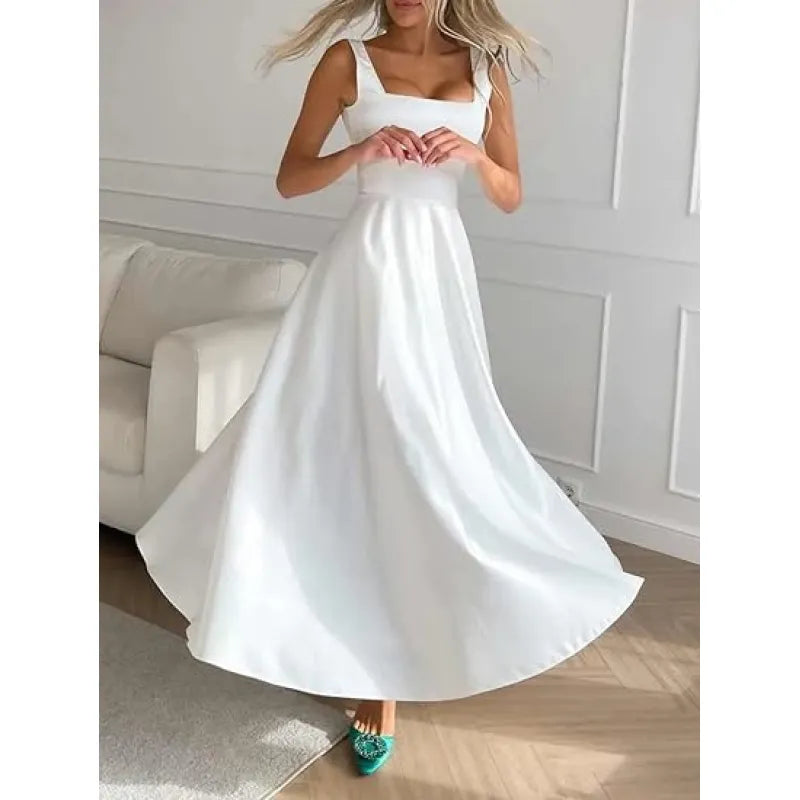 Robe blanche élégante longue, sans manches, portée par une femme dans un salon moderne. Mode féminine, tenue chic, style minimaliste.