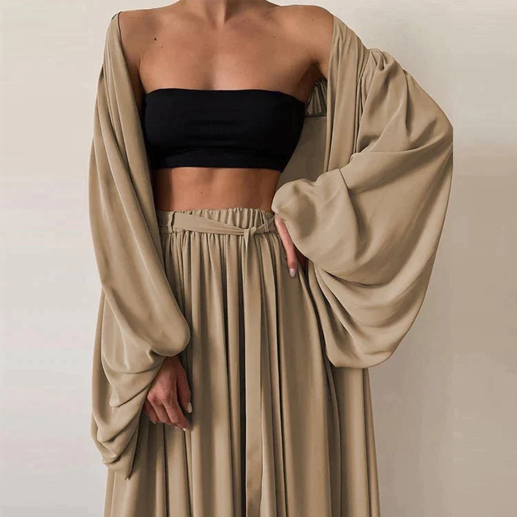 Femme portant une tenue élégante beige avec manches longues amples et haut noir. Mode chic, style minimaliste, vêtements tendance.