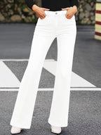 Pantalon blanc évasé femme, style rétro, sur fond urbain. Mode tendance, jeans taille haute, look chic et moderne.