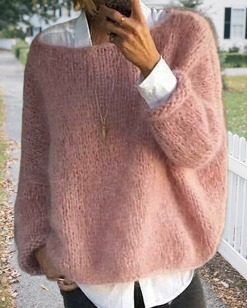 Femme portant un pull en laine rose ample, style décontracté, sur une chemise blanche, dans un cadre extérieur automnal. Mode féminine chic et cosy.