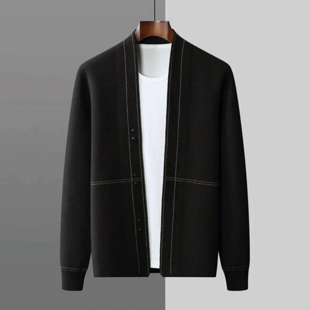 Cardigan noir élégant pour homme sur cintre, avec coutures blanches contrastantes, devant un fond gris. Mode masculine, vêtement chic, automne-hiver.