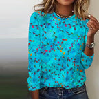 Femme portant un pull bleu à motifs floraux colorés, col rond, manches longues, style décontracté. Mode féminine tendance, look estival.