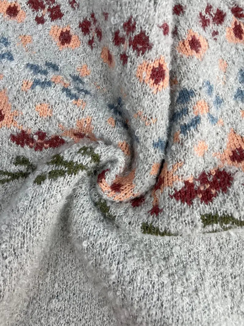 Tissu en laine tricotée avec motif floral multicolore, tons pastel et texture douce. Idéal pour mode hiver, vêtements chauds et confortables.