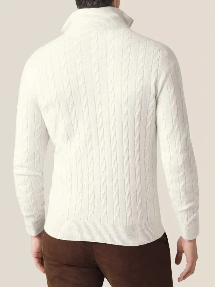 Homme portant un pull torsadé blanc en laine, manches longues, col montant, sur fond beige. Mode masculine élégante, tenue automne-hiver.