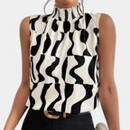 Blouse sans manches à col montant, motif noir et blanc ondulé, portée par une femme. Mode élégante, tendance, tenue chic.