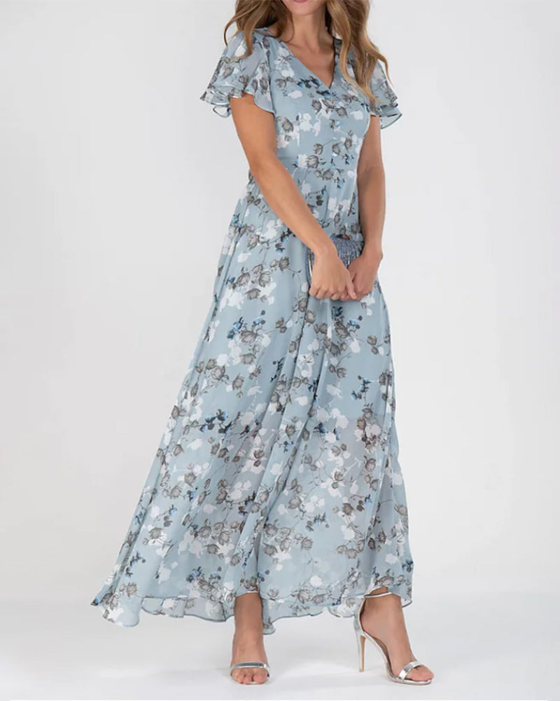 Robe longue fleurie bleue, manches courtes, col en V, portée par une femme, élégante et estivale, idéale pour soirées ou mariages.
