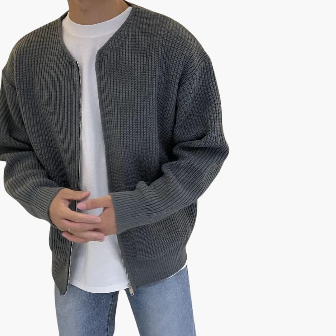 Homme portant un cardigan gris en maille, t-shirt blanc et jean bleu clair. Mode décontractée, style moderne, tenue automne-hiver.