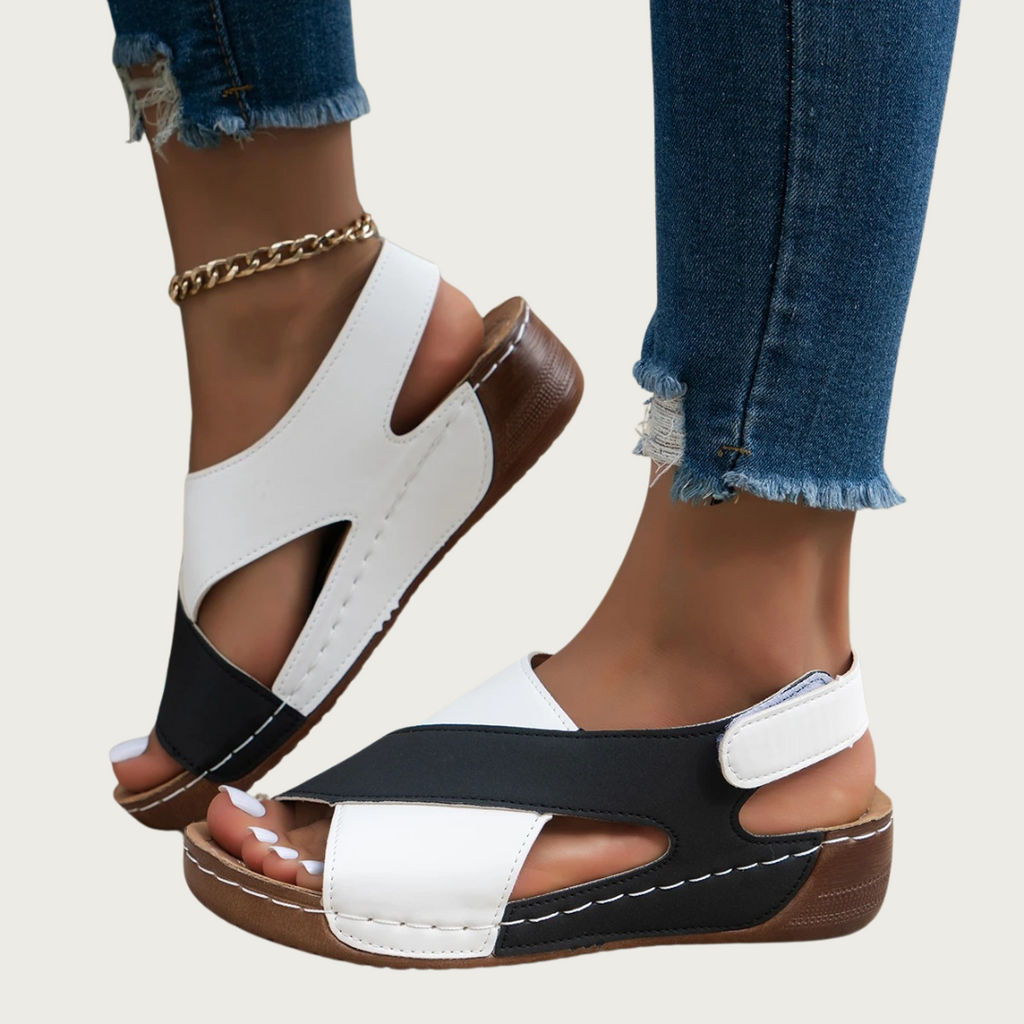 Sandales femme bicolores noir et blanc, talon compensé, portées avec un jean déchiré. Chaussures d'été tendance, confortables et élégantes.