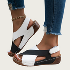 Sandales femme bicolores noir et blanc, talon compensé, portées avec un jean déchiré. Chaussures d'été tendance, confortables et élégantes.