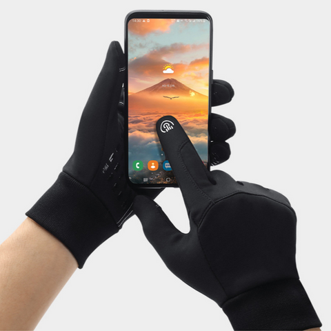 Gants tactiles noirs utilisant un smartphone avec écran allumé, montrant un paysage de montagne. Accessoire hiver, technologie écran tactile.