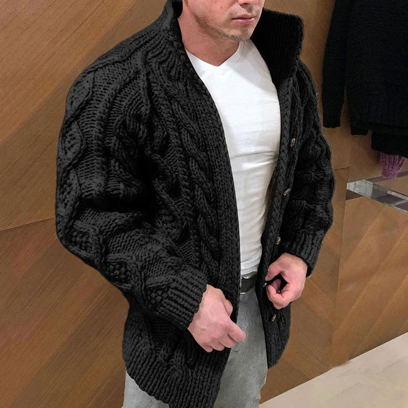 Homme portant un cardigan en tricot noir épais, col montant, boutons en bois, sur un t-shirt blanc. Mode masculine, style hivernal élégant.