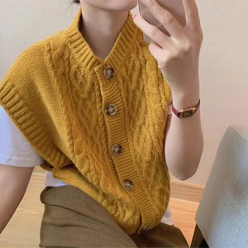 Femme portant un gilet en tricot jaune à boutons, posant avec un smartphone. Mode automne, style décontracté, tendance vêtements en laine.