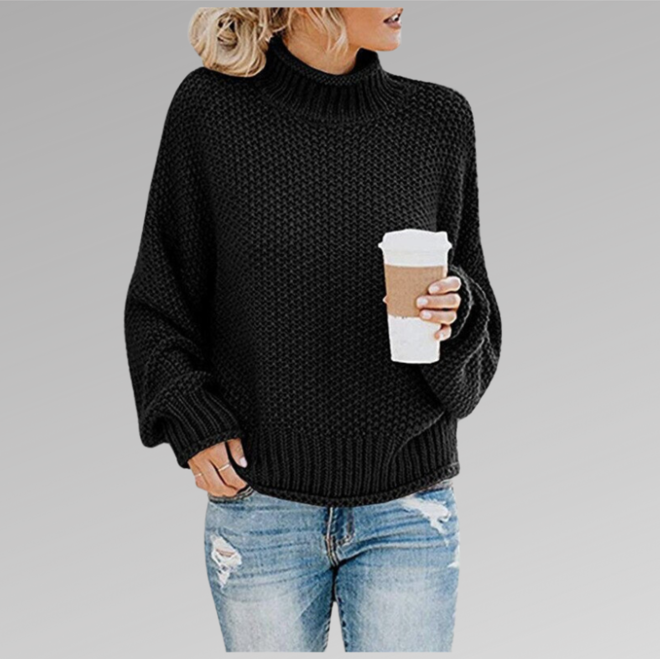Femme en pull noir à col roulé, tenant un gobelet de café, portant un jean déchiré. Mode automne-hiver, style décontracté tendance.