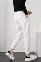 Pantalon blanc homme élégant, coupe ajustée, avec poches latérales, porté avec des baskets blanches et noires, style décontracté moderne.