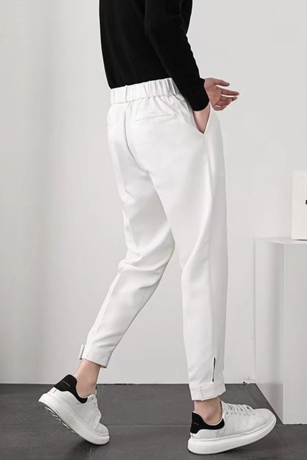 Pantalon blanc homme élégant, coupe ajustée, avec poches latérales, porté avec des baskets blanches et noires, style décontracté moderne.