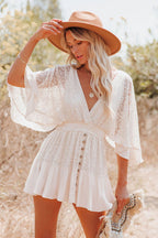 Femme en robe blanche en dentelle, chapeau marron, posant dans un champ ensoleillé. Mode bohème, été, style décontracté, nature.