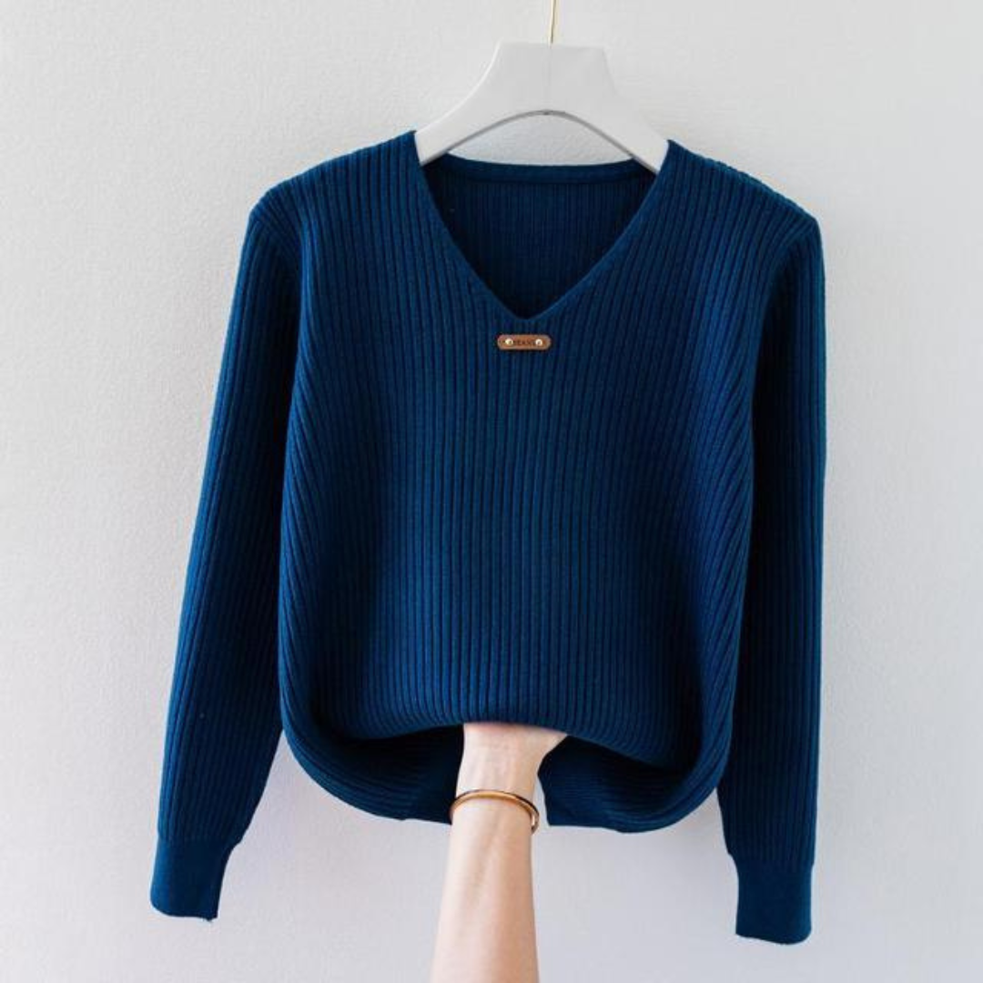 Pull bleu en tricot côtelé avec col en V, suspendu sur un cintre blanc. Mode automne-hiver, vêtement chaud et élégant pour femme.