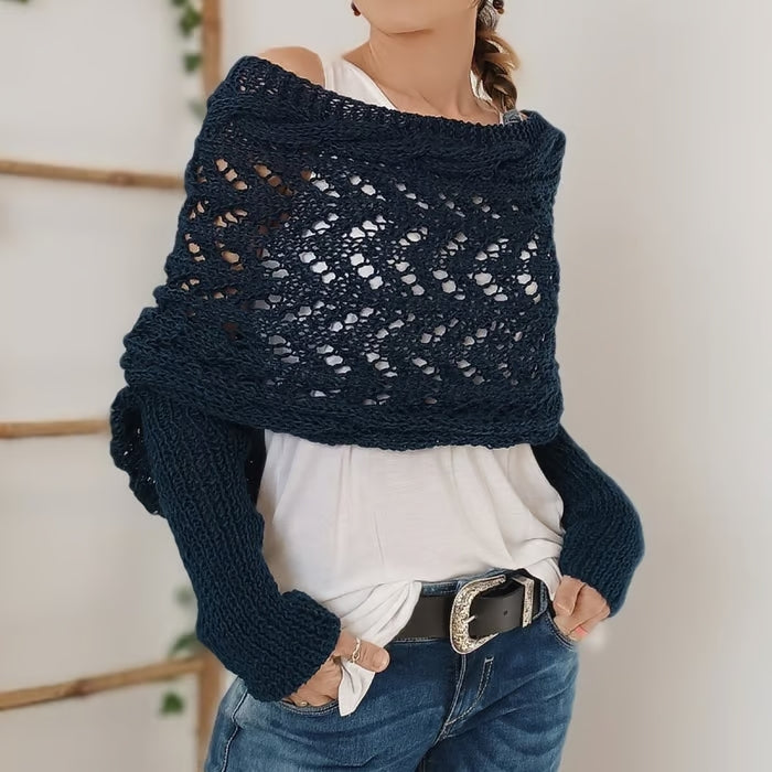 Femme portant un pull en crochet bleu marine, style bohème, avec un débardeur blanc et un jean décontracté. Mode automne, tendance tricot.
