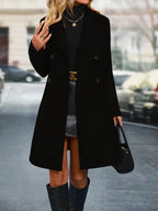 Femme portant un manteau noir élégant, jupe grise, bottes hautes et sac à main, marchant en ville. Mode automne chic, style urbain moderne.