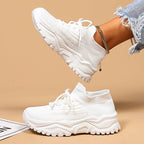 Baskets blanches modernes avec semelle épaisse, portées avec un jean déchiré. Chaussures de sport tendance pour femme, style décontracté et urbain.
