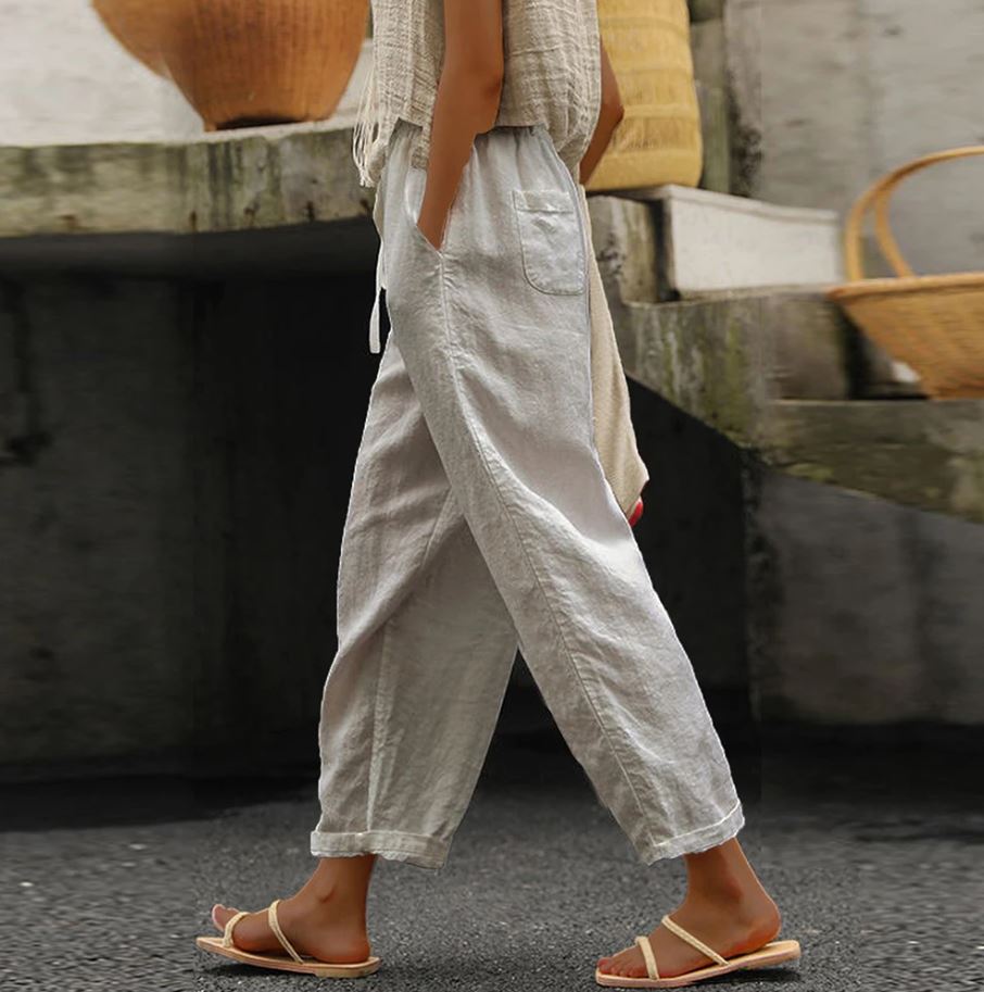 Pantalon en lin blanc pour femme, style décontracté, avec poches, porté avec des sandales. Mode estivale, confort et élégance.