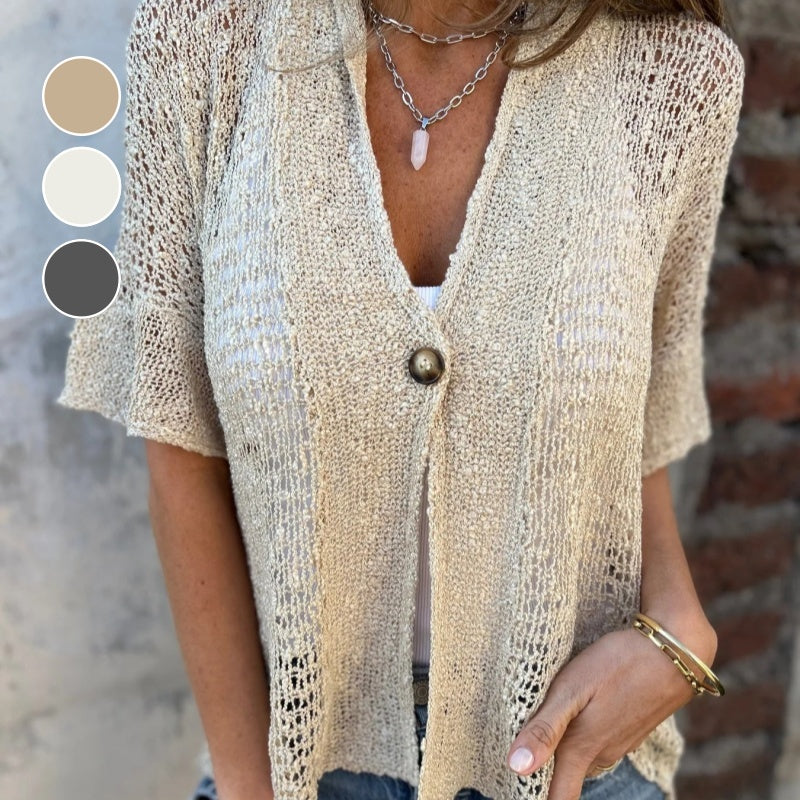 Femme portant un cardigan en maille beige avec bouton, collier en chaîne et bracelet doré. Mode décontractée, style bohème chic, tendance été.