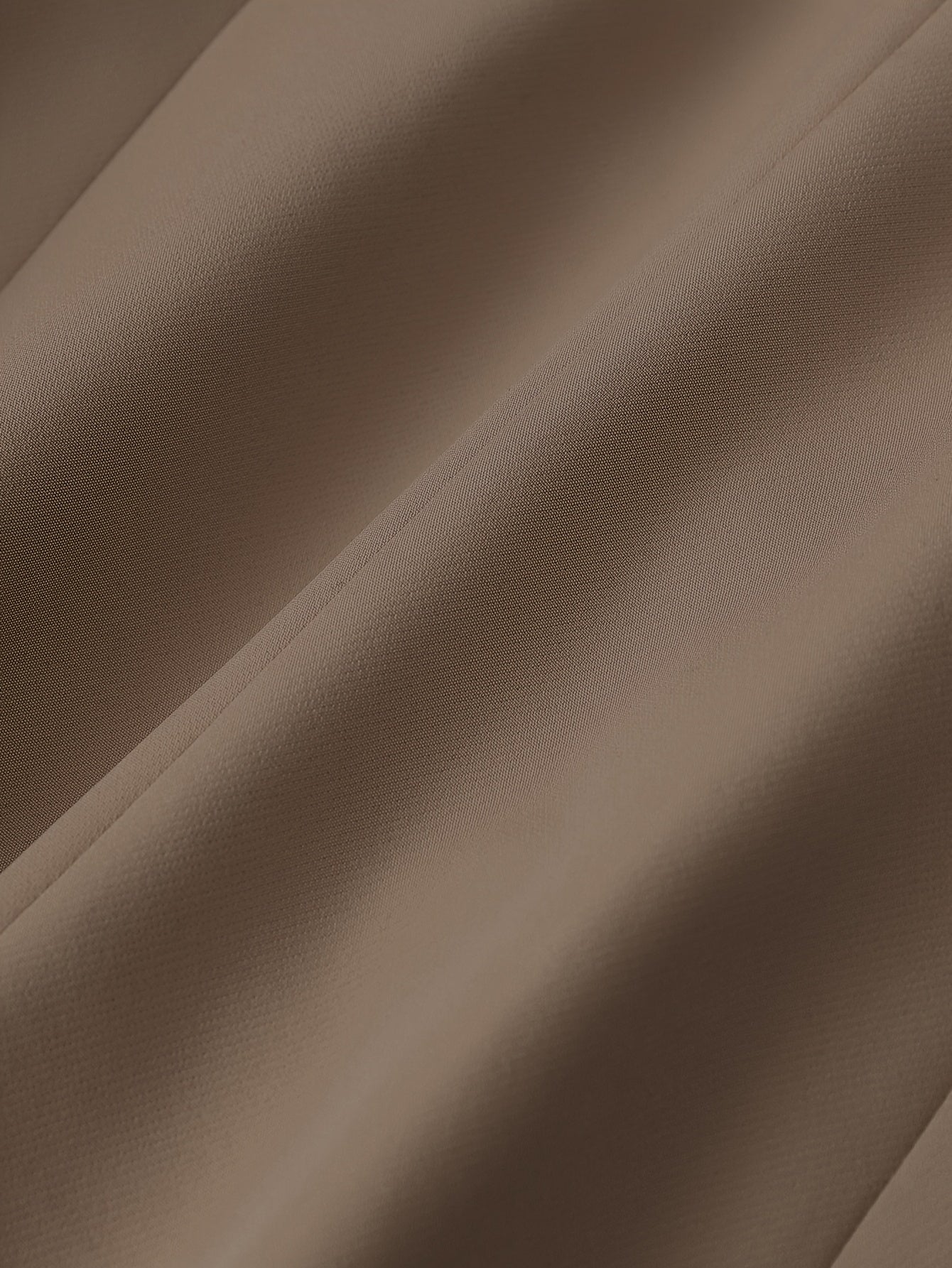 Tissu marron en gros plan, texture douce et plissée, textile élégant pour mode et décoration intérieure, fond neutre et chaleureux.