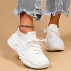 Baskets blanches tendance avec semelle épaisse, portées avec un jean déchiré. Chaussures de sport modernes pour un look décontracté et stylé.