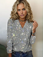 Jeune femme blonde portant un pull scintillant argenté, posant avec confiance. Mode féminine élégante, style moderne, look glamour.