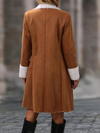 Manteau en daim marron pour femme avec col et poignets en fausse fourrure blanche, style élégant, mode automne-hiver, arrière-plan urbain flou.