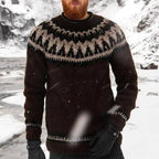 Homme portant un pull en laine islandais marron avec motifs traditionnels, debout dans un paysage enneigé. Mode hiver, vêtements chauds.