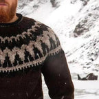 Homme barbu portant un pull en laine islandais traditionnel avec motif géométrique noir et blanc, fond de paysage enneigé. Mode hiver nordique.