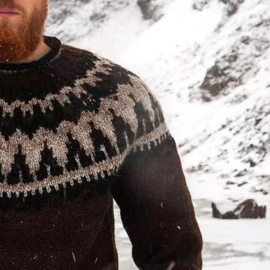 Homme barbu portant un pull en laine islandais traditionnel avec motif géométrique noir et blanc, fond de paysage enneigé. Mode hiver nordique.