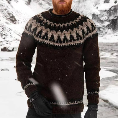 Homme barbu portant un pull en laine islandais noir avec motifs traditionnels, debout dans un paysage enneigé. Mode hiver, vêtements chauds.