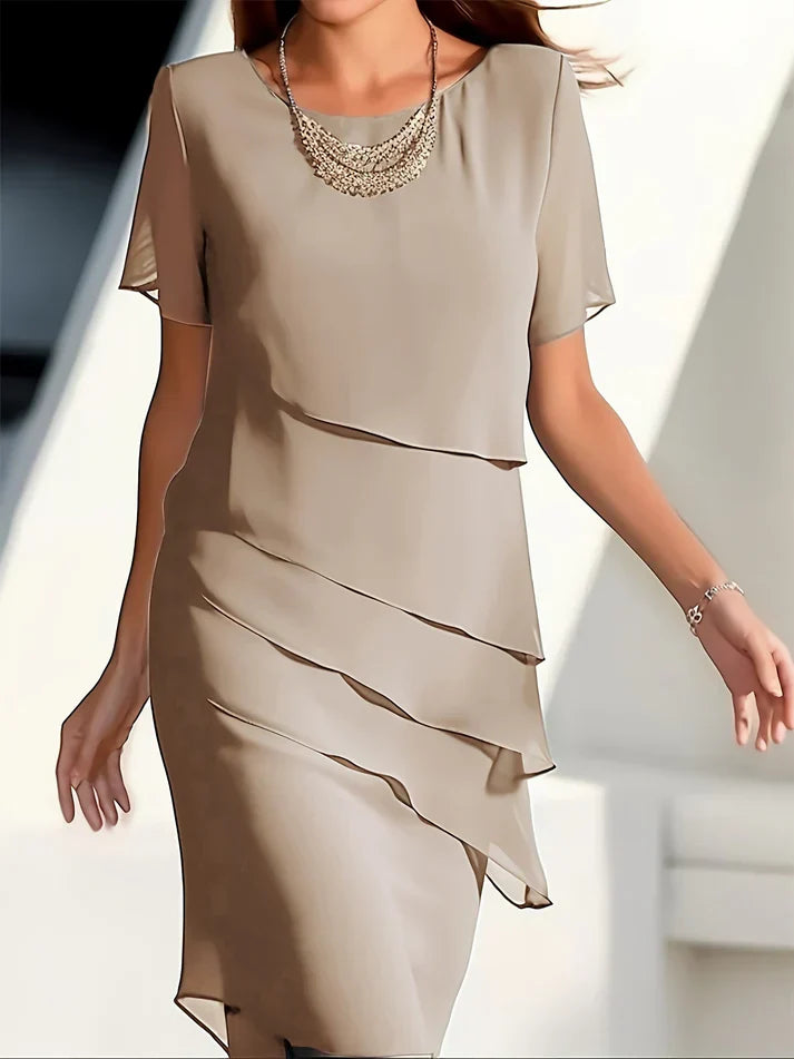 Robe élégante beige à volants superposés, manches courtes, collier argenté, style chic et moderne, mode féminine tendance.