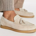 Mocassins en daim beige avec pampilles, semelle en caoutchouc, portés avec un pantalon à rayures. Chaussures élégantes pour homme.