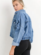 Femme portant une veste en jean bleu, manches retroussées, posant de profil. Mode décontractée, tendance vestimentaire, style denim.