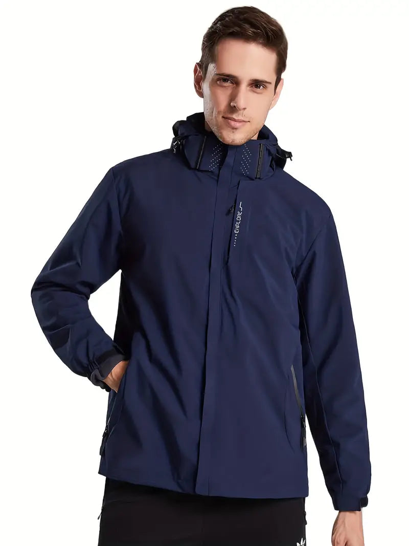 Homme portant une veste imperméable bleue avec capuche, poches zippées et logo visible. Mode masculine, vêtement d'extérieur, style décontracté.