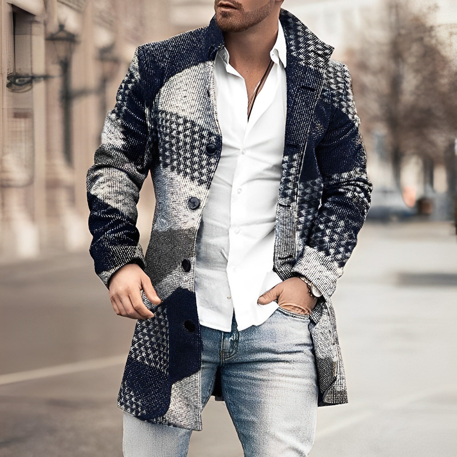 Homme portant un manteau patchwork bleu et gris, chemise blanche et jean, marchant en ville. Mode masculine élégante, style urbain chic.