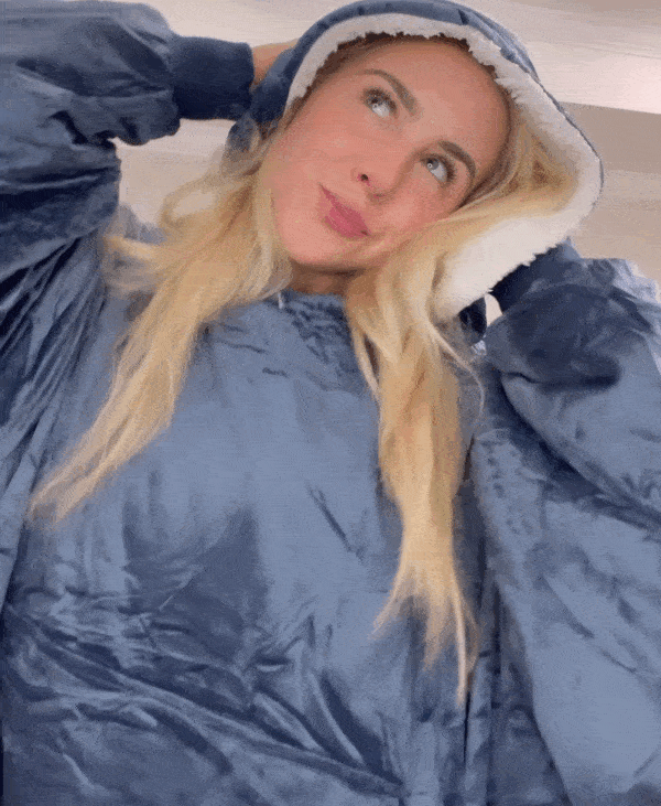 Jeune femme portant un sweat à capuche en polaire bleu, ajustant la capuche. Mode confortable, tenue d'intérieur, style décontracté.