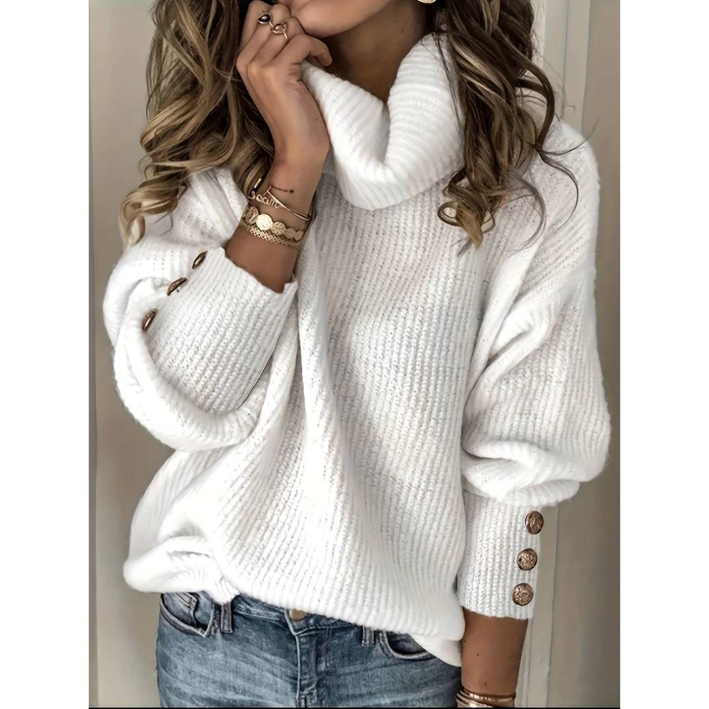 Femme portant un pull blanc à col roulé, manches longues avec boutons dorés, associée à un jean bleu. Mode automne-hiver, style décontracté chic.