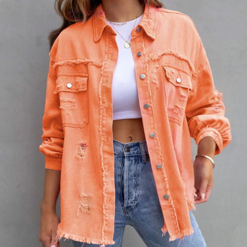 Veste en jean orange délavée pour femme, style décontracté, avec poches et boutons, portée sur un t-shirt blanc et un jean bleu. Mode tendance.