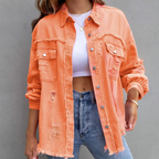 Veste en jean orange délavée pour femme, style décontracté, avec poches et boutons, portée sur un t-shirt blanc et un jean bleu. Mode tendance.