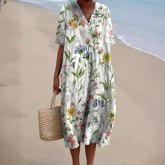 Robe d'été fleurie, manches courtes, portée par une femme sur la plage, avec sac en osier. Mode plage, tenue décontractée, style estival.
