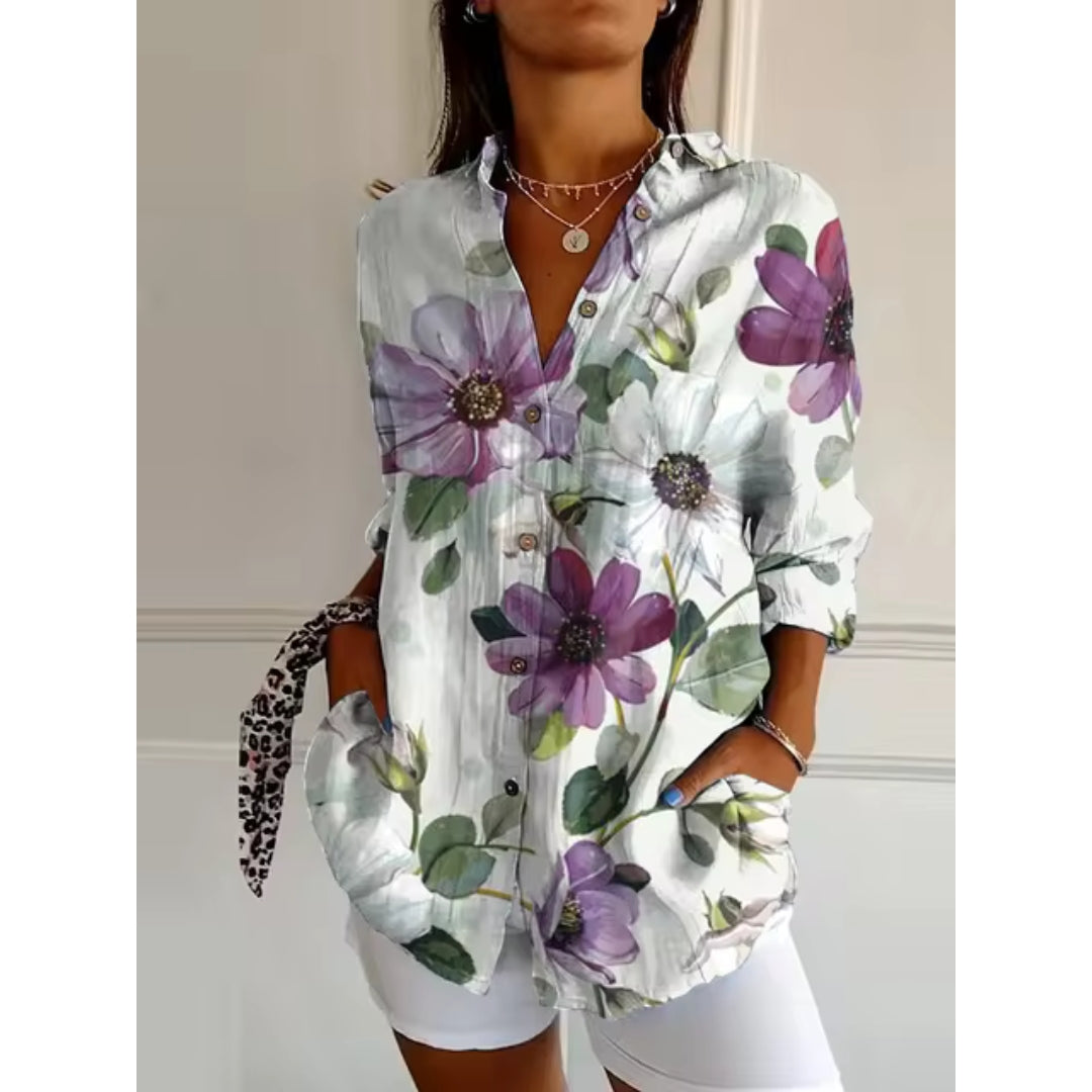 Chemisier femme à manches longues avec imprimé floral violet et blanc, col ouvert, boutons, porté avec short blanc. Mode féminine élégante.