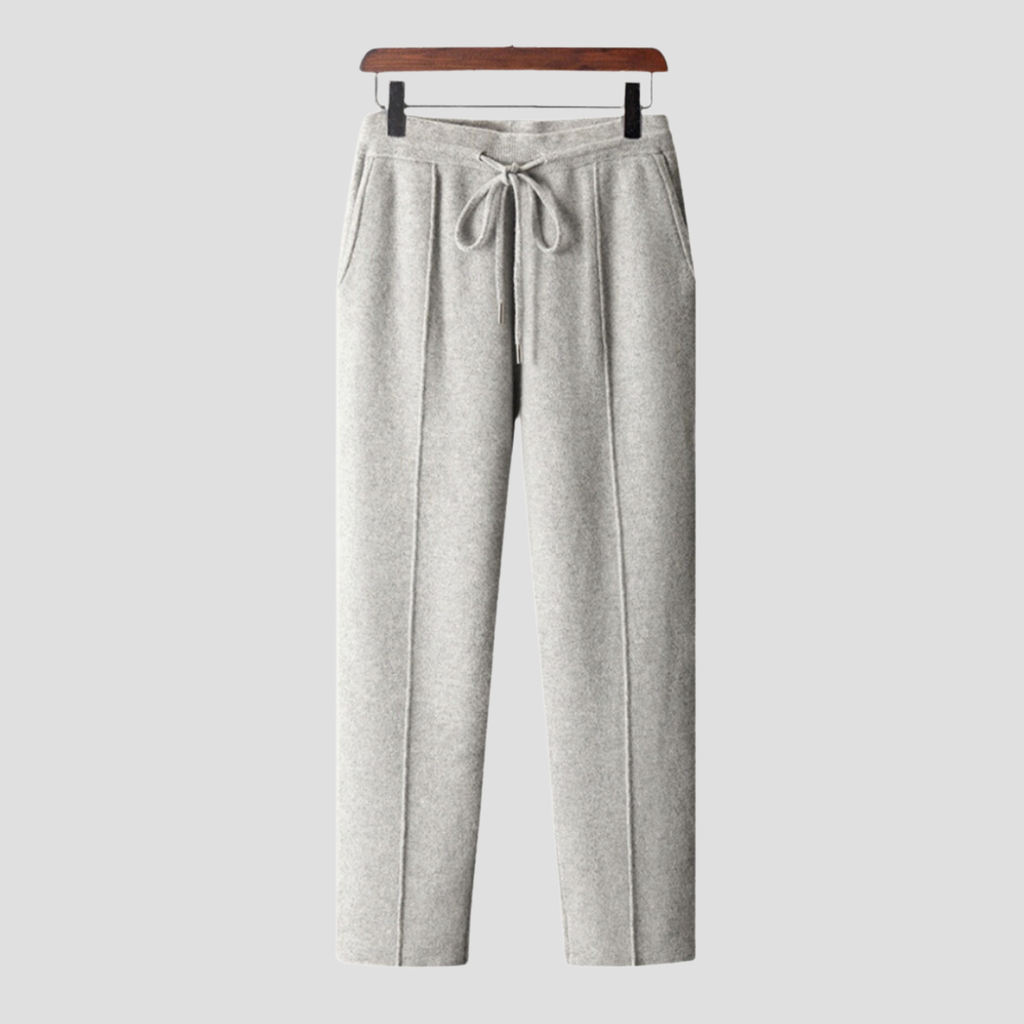 Pantalon gris en laine, coupe droite, avec cordon de serrage à la taille, poches latérales, suspendu sur un cintre en bois. Mode hiver élégante.