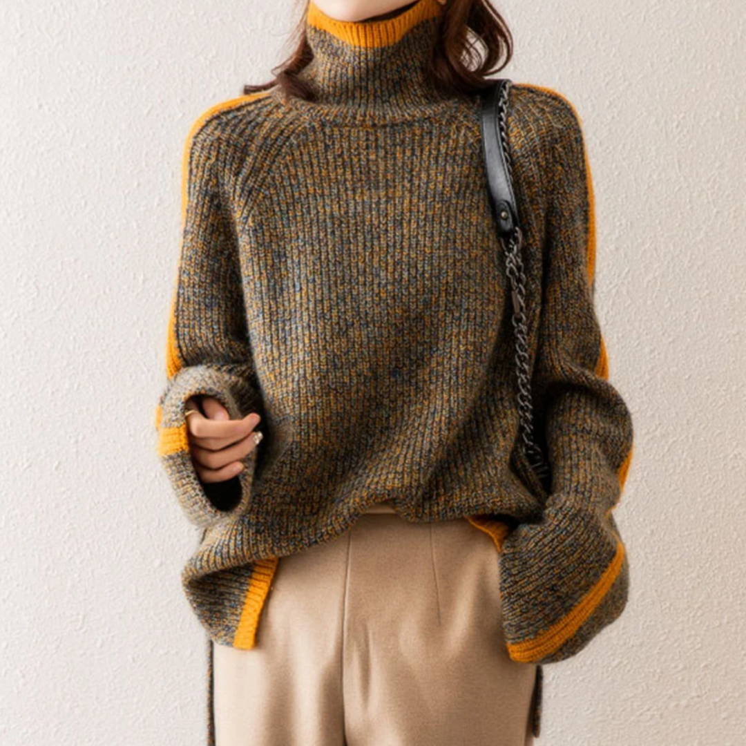Femme portant un pull en laine à col roulé marron et orange, manches longues, avec un sac à bandoulière noir, sur fond beige. Mode automne-hiver.