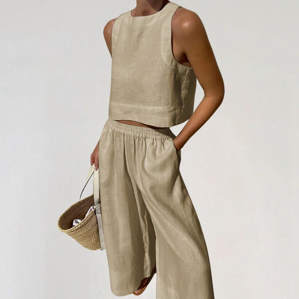 Femme portant un ensemble en lin beige, composé d'un haut sans manches et d'un pantalon ample, tenant un sac en osier. Mode estivale élégante.