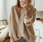 Femme portant un cardigan beige en laine, manches longues, devant un miroir. Style décontracté, mode automne-hiver, intérieur moderne.